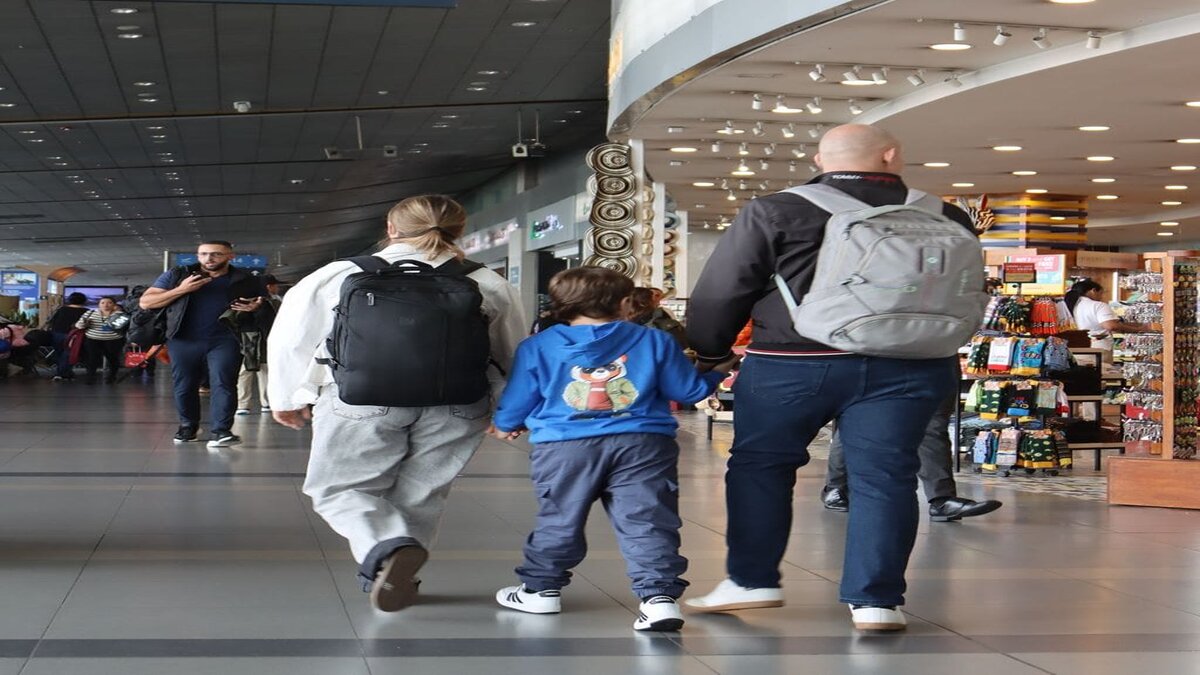 Familia conformada por padre, madre e hijo caminando por el aeropuerto 