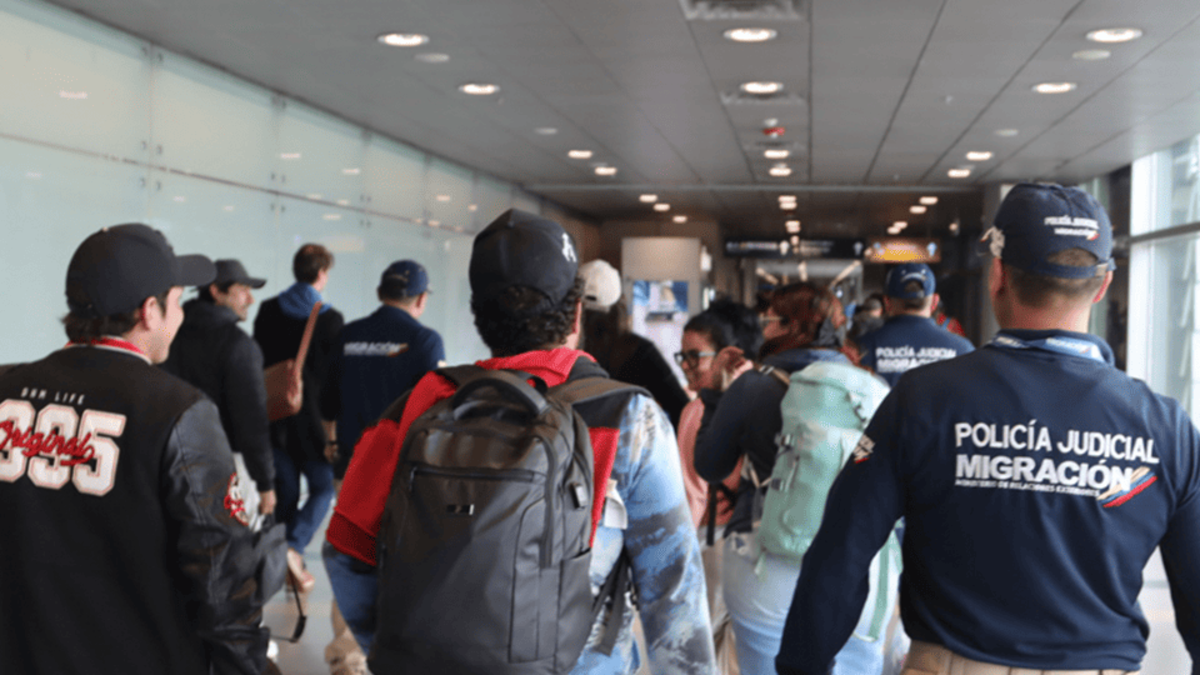 Oficiales de Migración Colombia caminando entre la gente en el aereopuerto